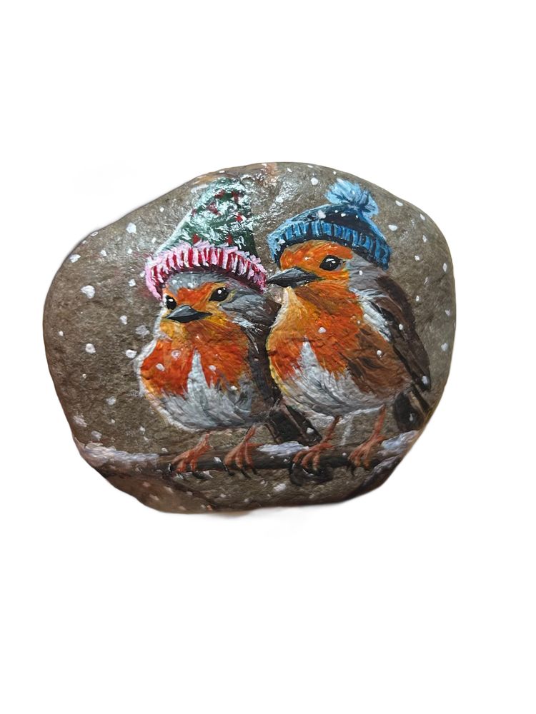 Two robins with winter hats painted on a stone